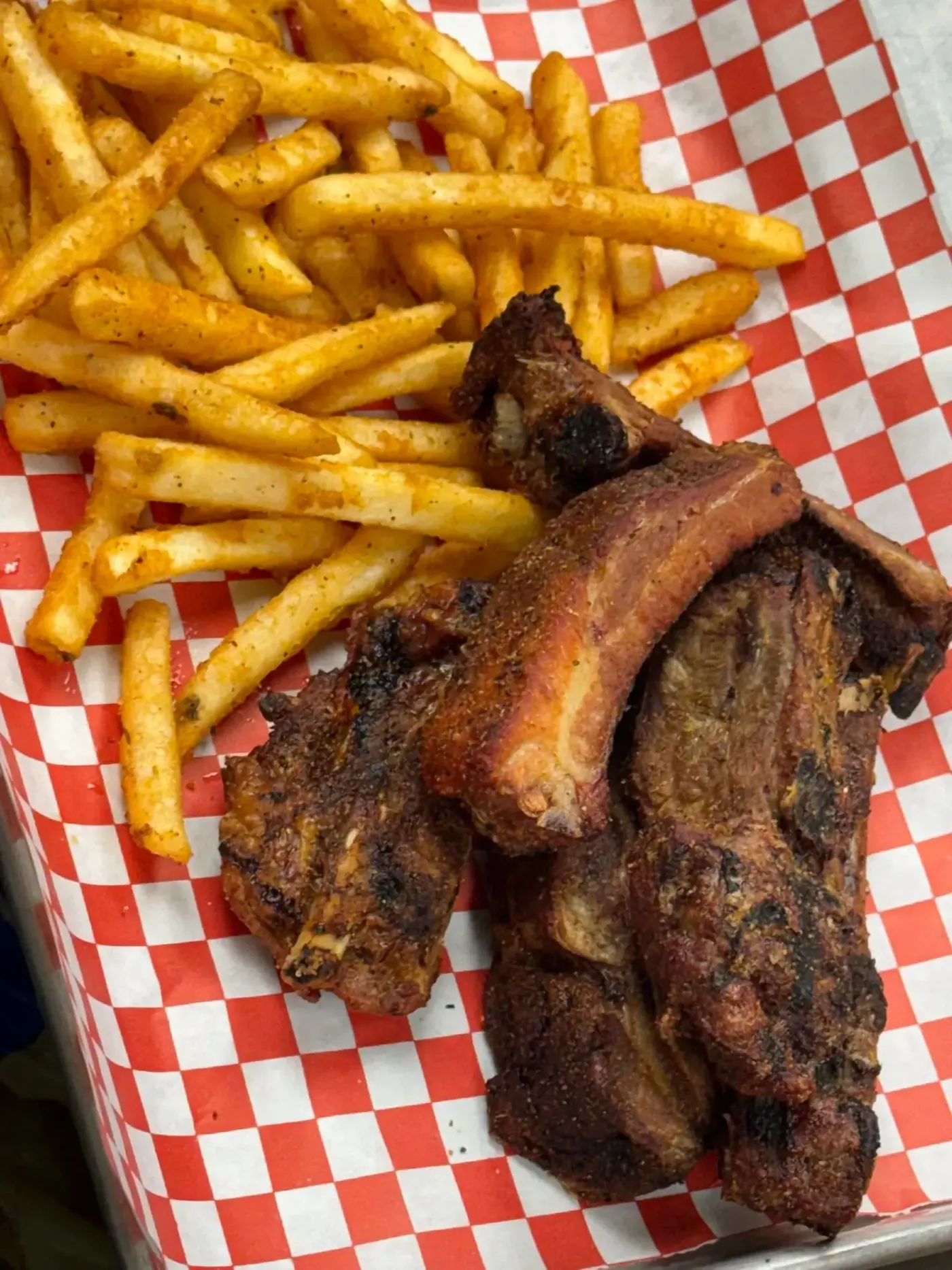 Smoked rib tips with seasoned fries in a checkered basket